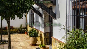 Une villa de style rustique dotée d’un patio carrelé, de plantes en pot et d’une enseigne indiquant « Casa Rural ».