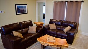 A living room with two dark brown leather sofas, a wooden coffee table, and a framed picture on the wall.