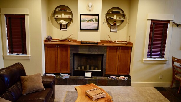 A living room with a fireplace, wooden shelves, and a leather couch.