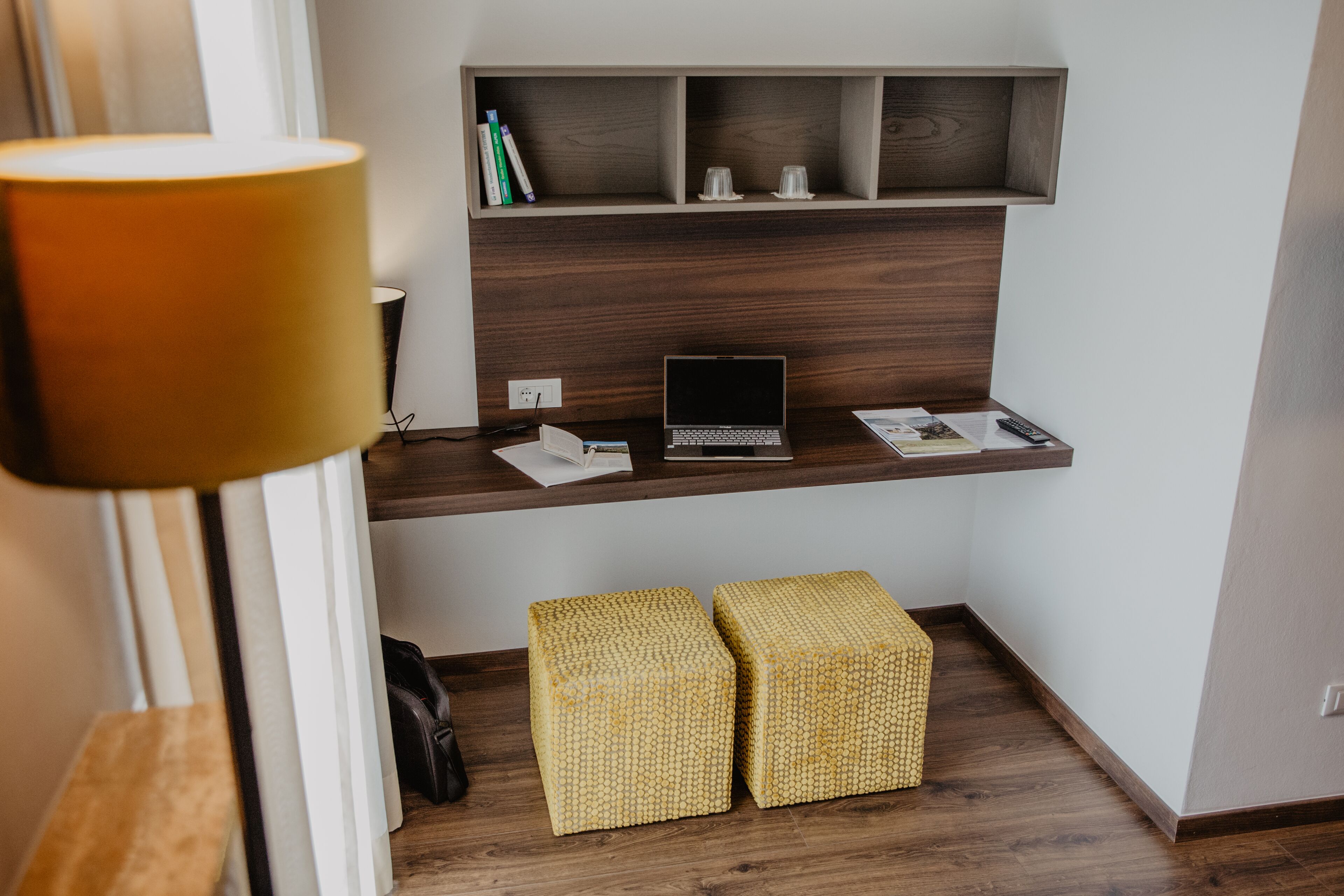 A modern workspace with a laptop, a desk lamp, and two woven stools.