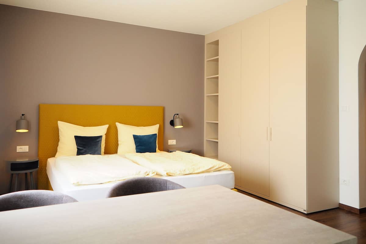 Un dormitorio moderno con cama, lámparas de noche, armario y mesita de noche.