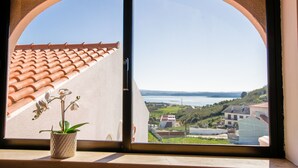 Ein Fenster mit Blick auf ein Ziegeldach und ein Topf mit einer Orchidee.