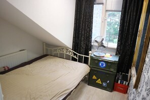 A bedroom with a bed, a window with curtains, a fan, and storage boxes. - Lake house 74 luxury accommodation with iR Sauna (Warmond)