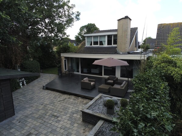 A modern house with a patio area featuring outdoor furniture and a large umbrella.