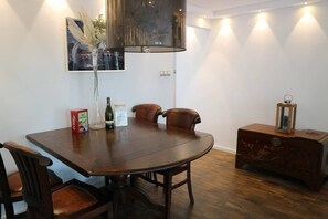 A dining area with a round table, two chairs, a vase with flowers, a bottle, and a box. - Lake house 74 luxury accommodation with iR Sauna (Warmond)