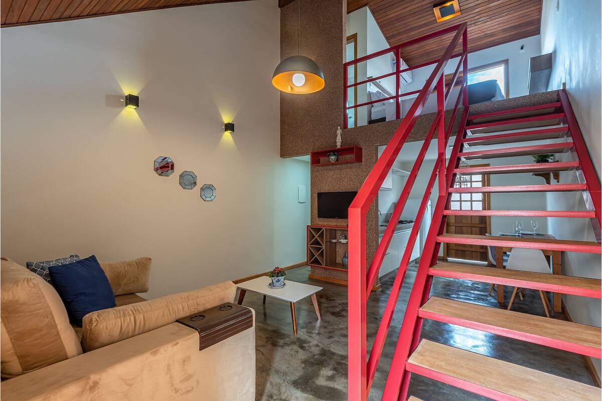 Ein modernes Wohnzimmer mit einer roten Treppe, einem Sofa, einem kleinen Tisch und Wandleuchten.