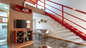 Een modern interieur met een rode trap, een flatscreen televisie en een eethoek.