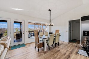 Enjoy meals in this spacious dining area with a large table and comfortable chairs, offering a view of the outdoors.