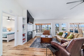 Relax in this inviting living room with a large window offering a view of the outdoors, a comfortable sofa, and a flat-screen TV.