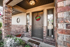 Welcome to a charming entryway with a brick exterior and a cozy porch.