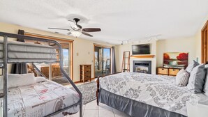 Quarto com cama, ventoinha no teto, televisão e lareira.