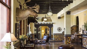 A lobby with a large moose head mounted on the wall, a chandelier, and a tiled floor.