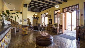 A lobby with a tiled floor, a large round ottoman, a reception desk with a plant, and a mounted deer head.