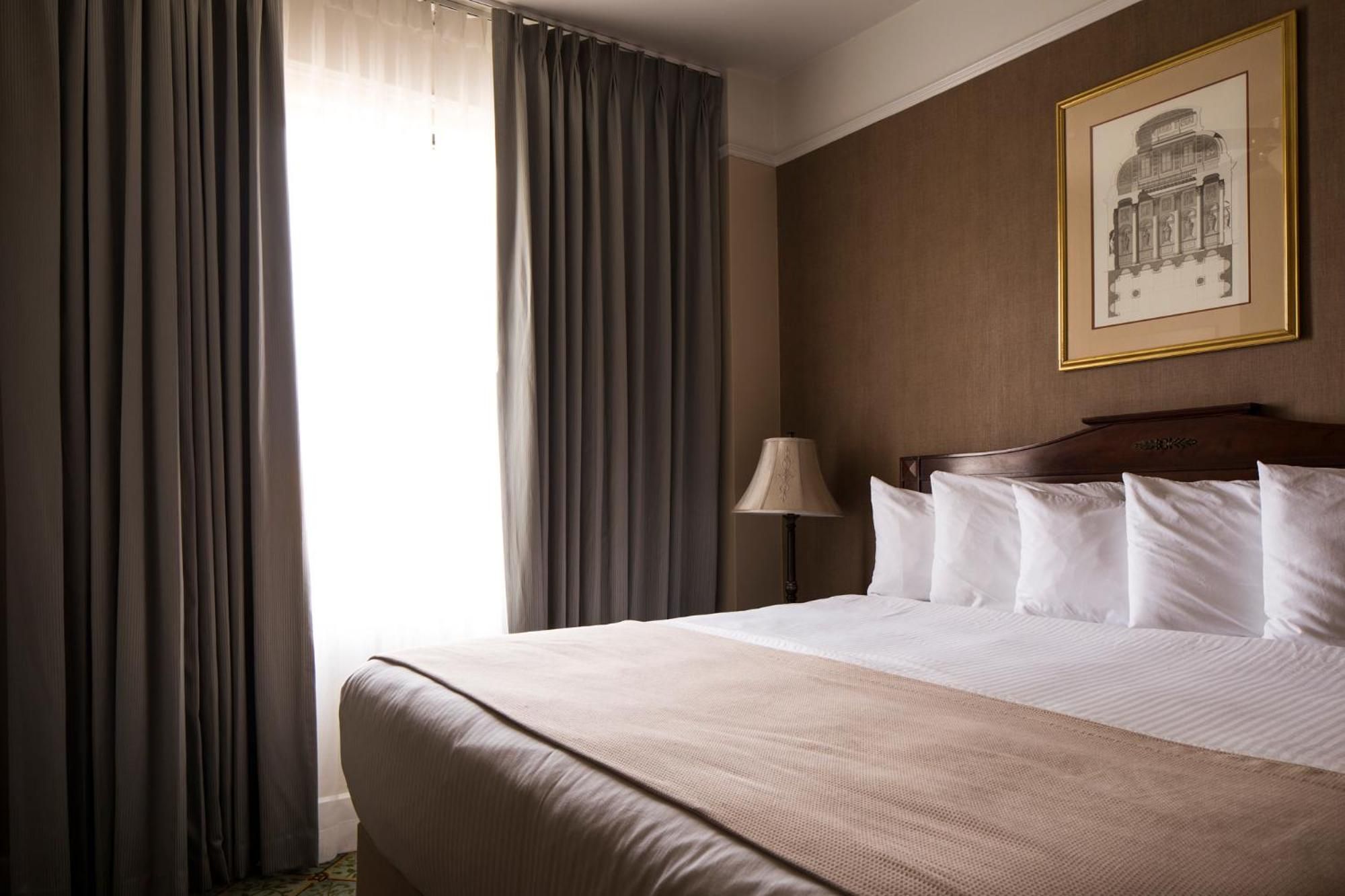 Una camera d'albergo con un letto grande, una lampada e un quadro incorniciato al muro.