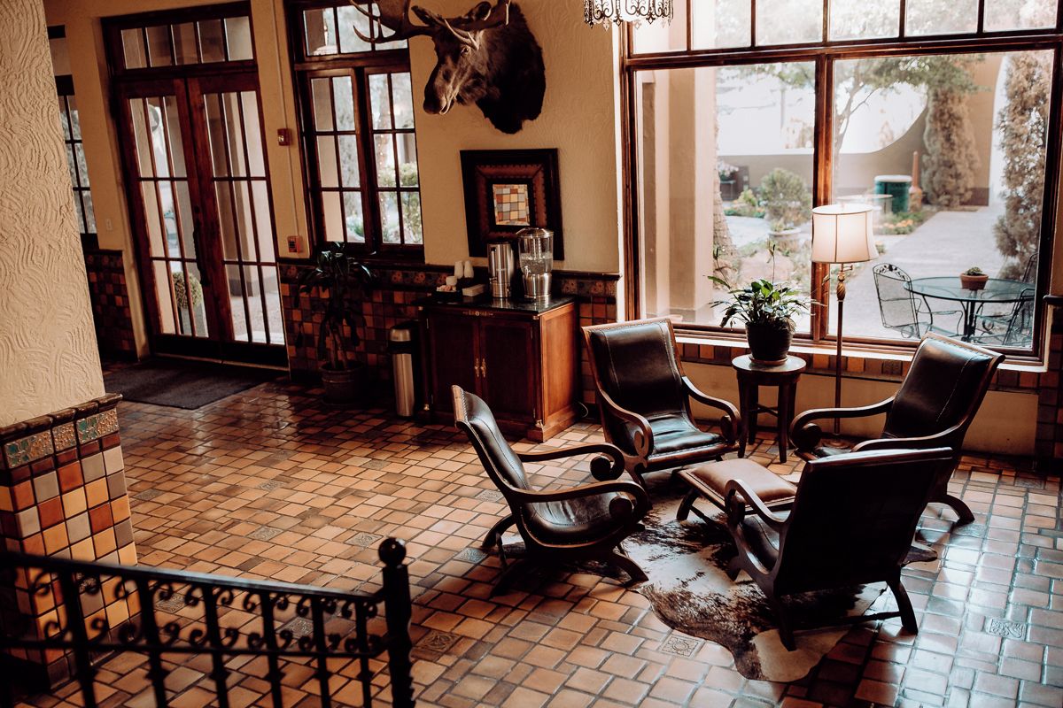 A room with a tiled floor, a mounted animal head on the wall, and a table with chairs.