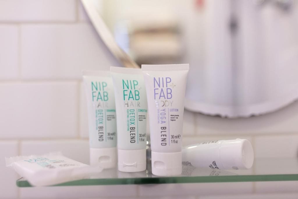Three NIP FAB hair, body, and yoga blend products on a bathroom counter.