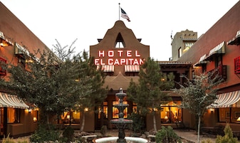 Hotel El Capitan with a central fountain, surrounded by trees and outdoor seating areas.