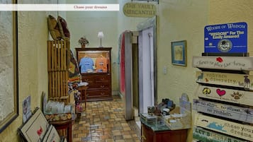 Um corredor com um armário de madeira, uma placa indicando 'THE VAULT MERCANTILE' e uma parede com letreiros motivacionais.