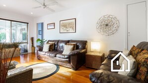 A modern living room with a leather sofa, a side table with a lamp, and a decorative wall piece. - Simplicity & Serenity *1 NIGHT FREE* Charming Retreat, no Govt Tax (Blairgowrie)