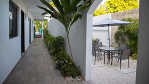 A corridor with a dining area featuring a table and chairs, surrounded by plants and a large umbrella. - Margarett Hotel (Valladolid)