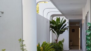 A corridor with potted plants, white columns, and a tiled floor. - Margarett Hotel (Valladolid)