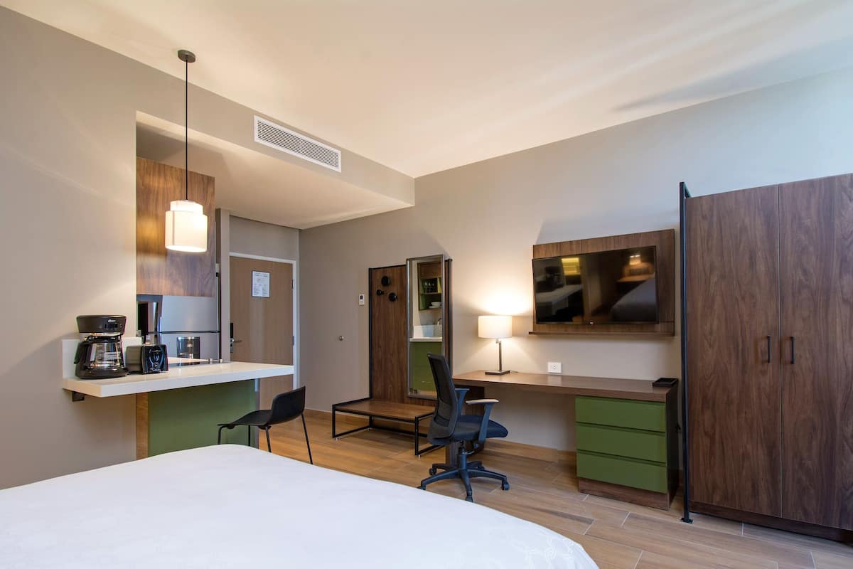 Een hotelkamer met een bed, bureau, stoel en kledingkast.