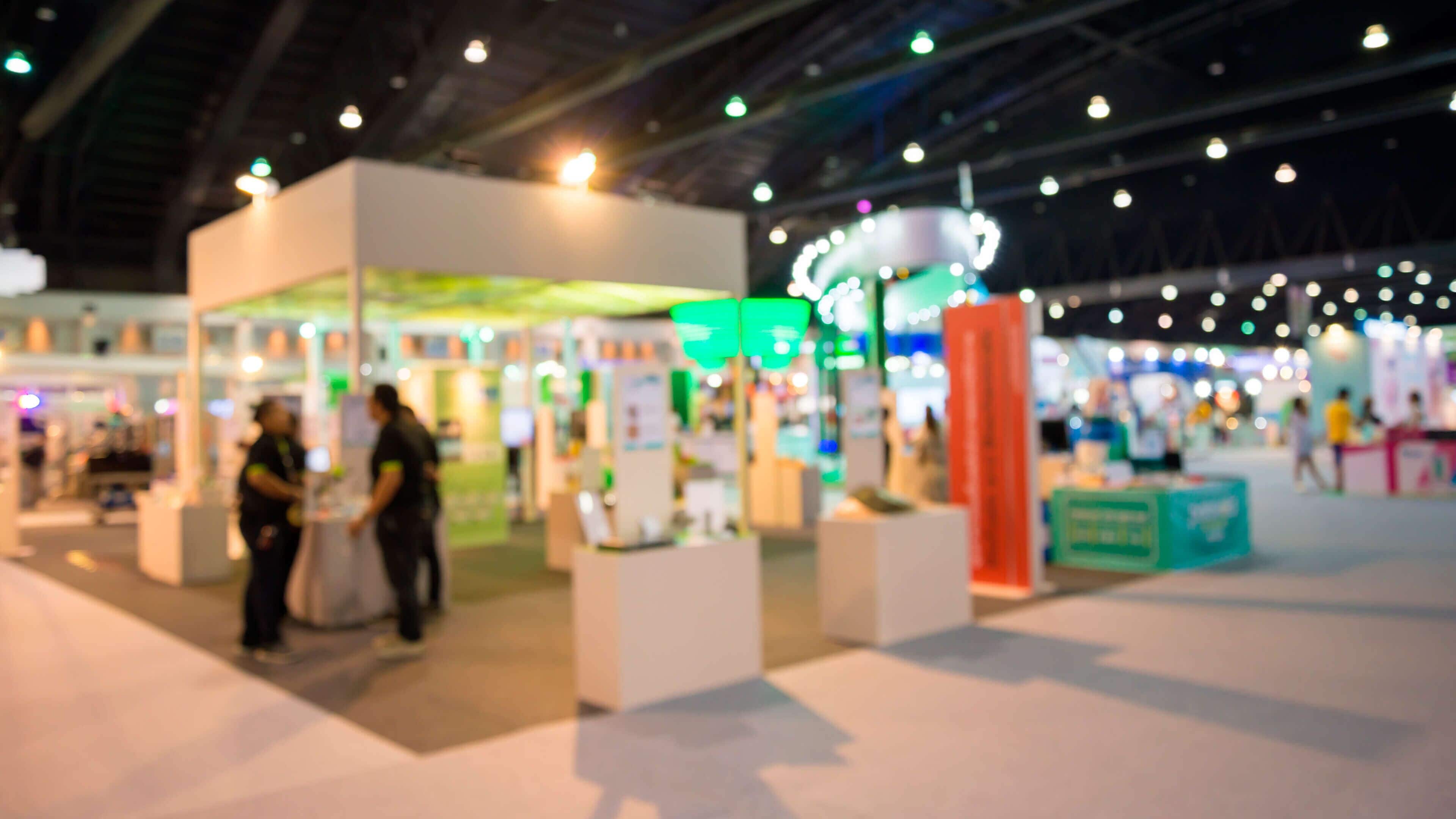 Un vaste espace intérieur comprenant de nombreux stands et présentoirs, probablement dans le cadre d’un salon professionnel ou d’une exposition.