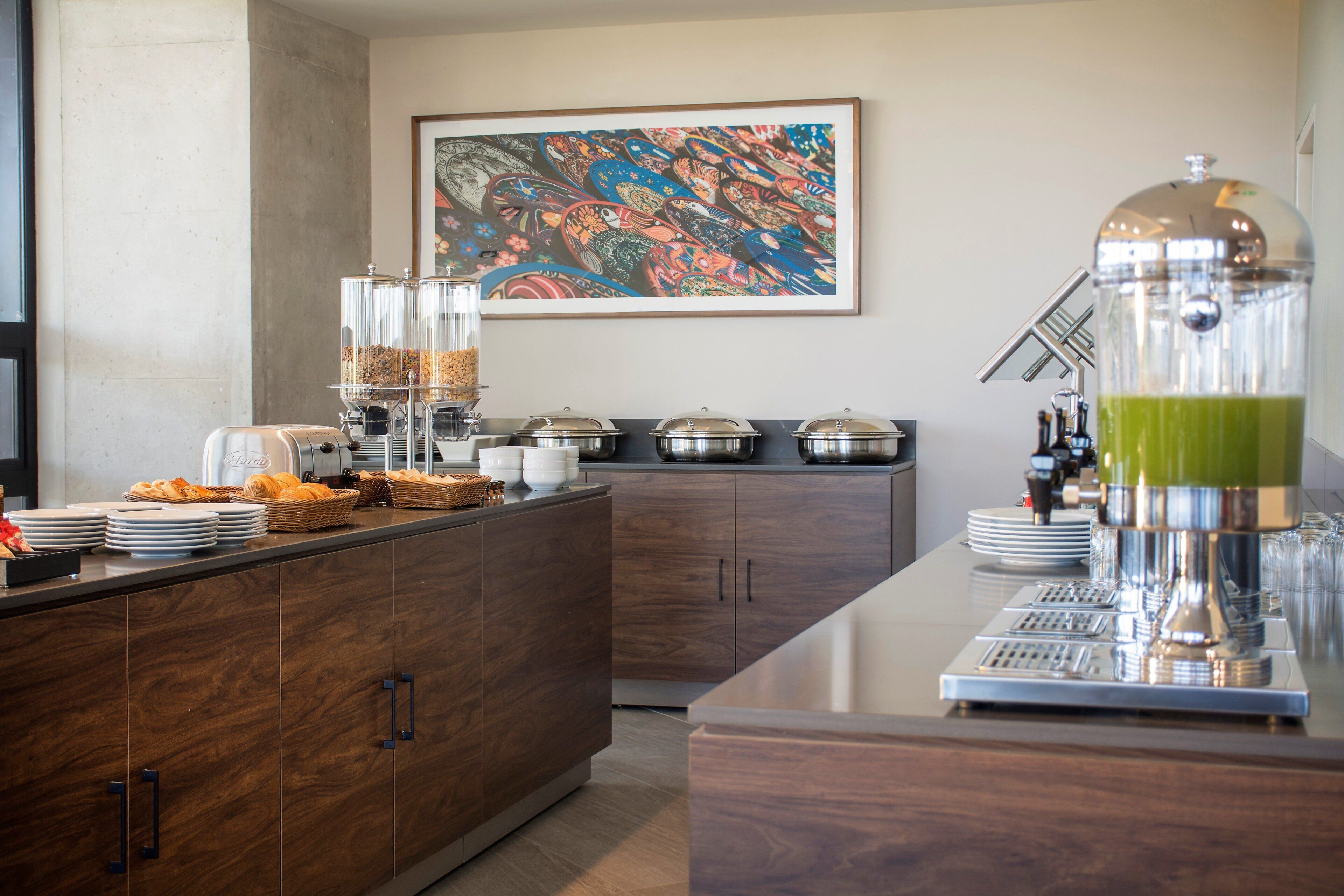 Une cuisine moderne avec un espace buffet, comprenant une machine à café, des récipients pour aliments et un distributeur de jus.