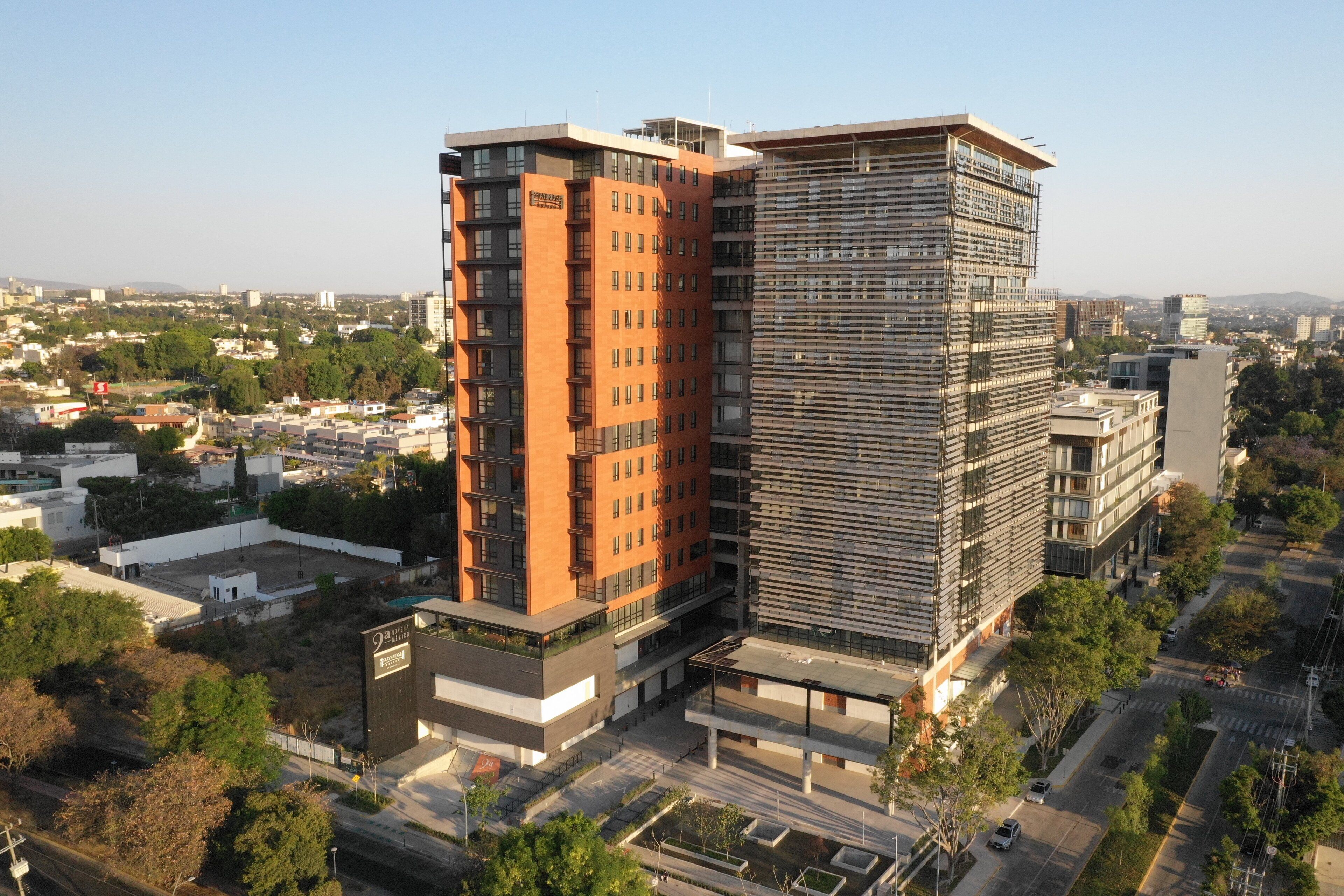 A modern high-rise building with a mix of glass and brick facades, surrounded by a cityscape.