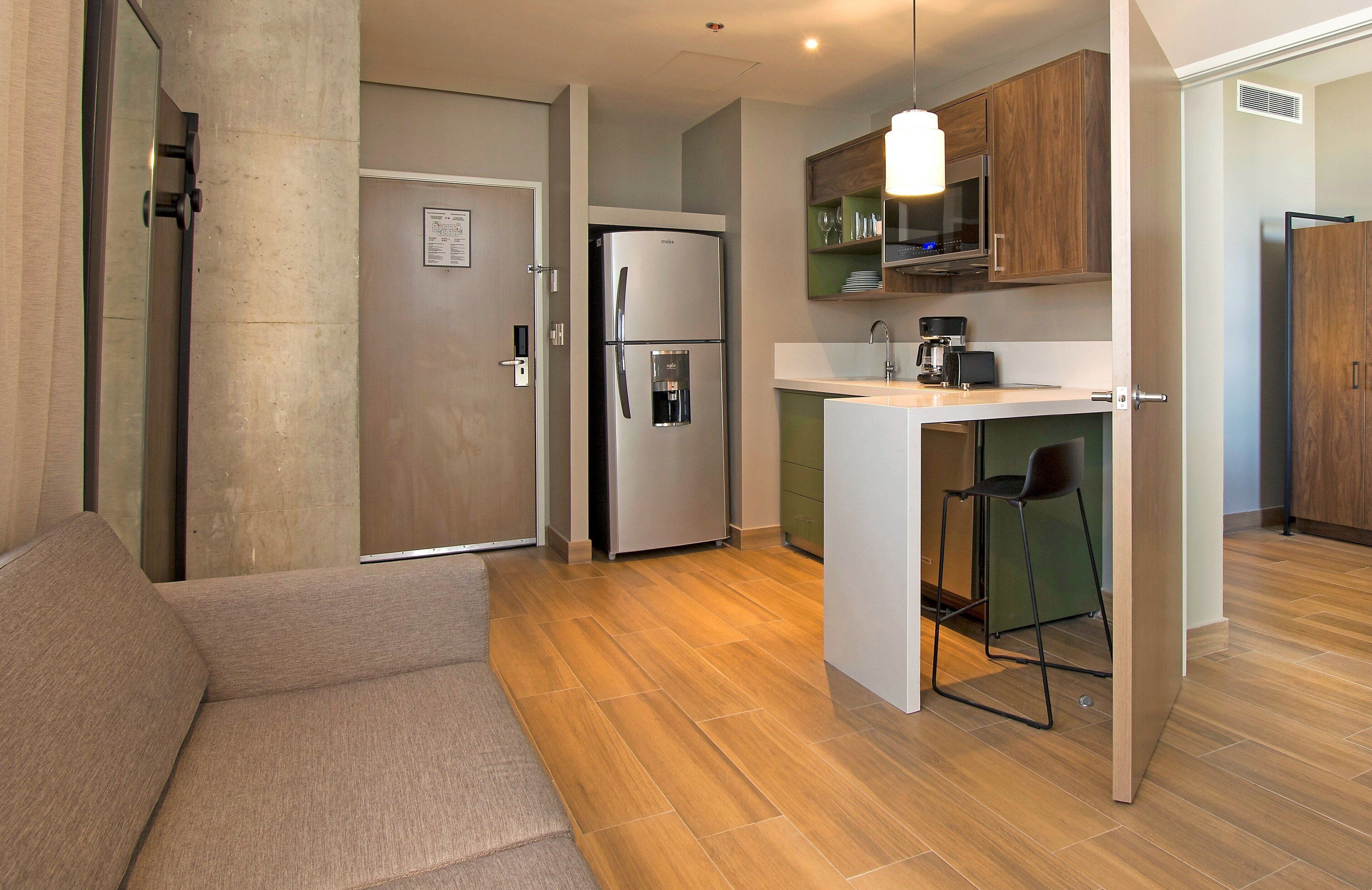 Un espacio habitable compacto con kitchenette, sofá y comedor.
