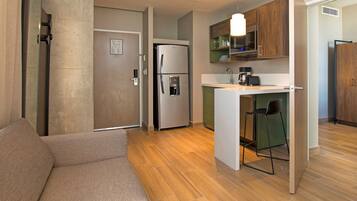 Un espacio habitable compacto con kitchenette, sofá y comedor.