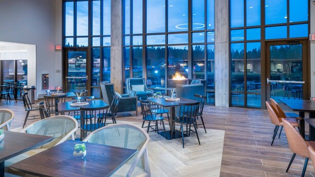 A spacious indoor dining area with large windows, modern furniture, and a visible fire feature. - SpringHill Suites by Marriott Island Park Yellowstone (Island Park)