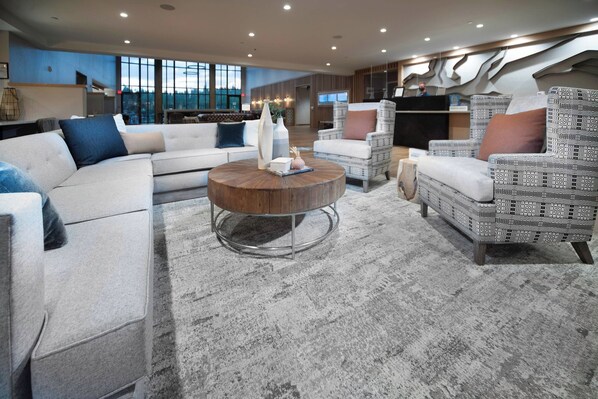 Una sala moderna con un sofá modular, sillones estampados y una mesa de centro redonda.