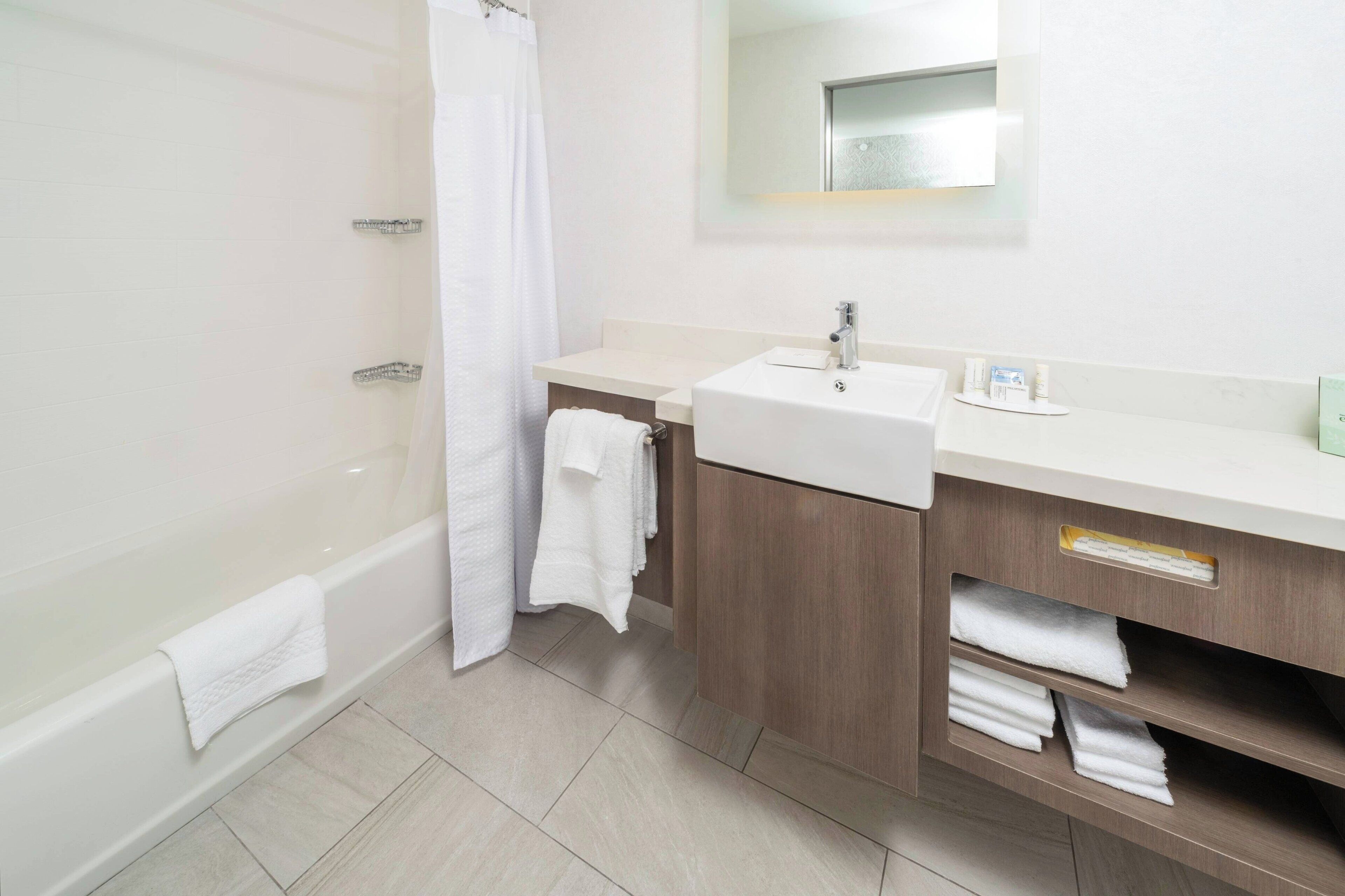 Une salle de bain moderne équipée d’une baignoire, d’un lavabo et d’un meuble-vasque avec des étagères pour les serviettes.