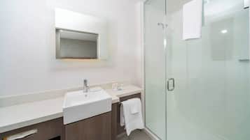 Un baño moderno con cabina de ducha de vidrio, un lavabo blanco y un espejo sobre el mueble.