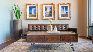A living room with a dark brown leather sofa, a wooden coffee table with drawers, and three framed pictures on the wall.