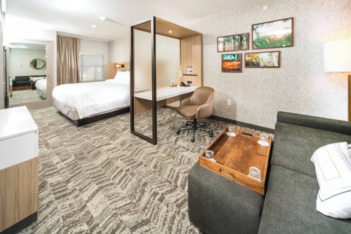 Een hotelkamer met een bed, bureau, stoel en een bank.