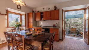 Una cucina con mobili in legno, un tavolo da pranzo con sedie, un lampadario e vista all'esterno.