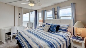 Ein Schlafzimmer mit Bett, Schreibtisch, Sessel, Nachttisch und Deckenventilator.