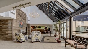 Eine geräumige Lobby mit hoher Decke, einer Rezeption, einer Sitzgelegenheit und einem großen Fenster mit Blick auf die Straße.
