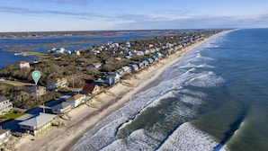 Une zone résidentielle côtière avec des maisons le long de la plage, un ciel dégagé et une mer calme.