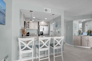 A modern kitchen with white cabinetry, a central island with bar stools, and pendant lighting.