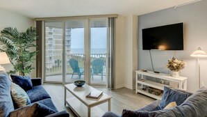 Un salon moderne avec balcon, un téléviseur à écran plat et une console blanche.