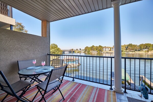 A balcony with a table and chairs, overlooking a body of water with boats and buildings in the background. - Great view, on the water (Hot Springs)