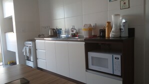 Eine moderne Küche mit weißen Schränken, einer Mikrowelle, einer Kaffeemaschine und einem Wasserkocher auf der Arbeitsfläche.