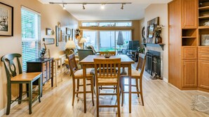 A spacious kitchen with wooden cabinets, a dining area with a table and chairs, and a view of the backyard through large windows. - JL 615: Quiet close to pool and beach, free Wi-Fi! (Birch Bay)
