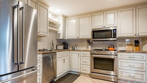 A modern kitchen with stainless steel appliances, white cabinetry, and a tiled backsplash. - JL 615: Quiet close to pool and beach, free Wi-Fi! (Birch Bay)