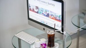 A computer monitor displaying a hotel website, a keyboard, and a glass table with a beverage and a small flower. - Parkroyal Suites Bangkok (Bangkok)