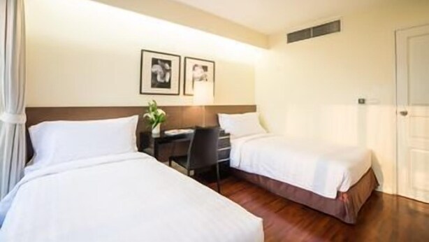 A hotel room with two beds, a desk, and a chair. - Parkroyal Suites Bangkok (Bangkok)