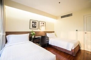 A hotel room with two beds, a desk, and a chair.